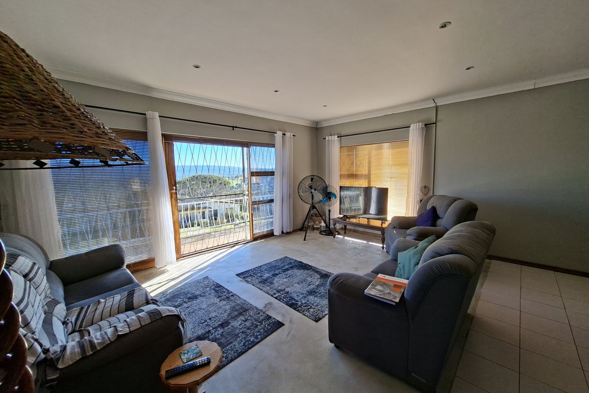Spacious living room featuring tiled flooring, recessed lighting, and a large sliding glass door providing access to an outdoor area with scenic views.