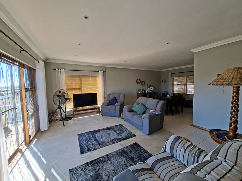 Spacious open-plan living and dining area featuring tiled flooring, recessed downlighting, and large sliding glass doors providing natural light and outdoor access.