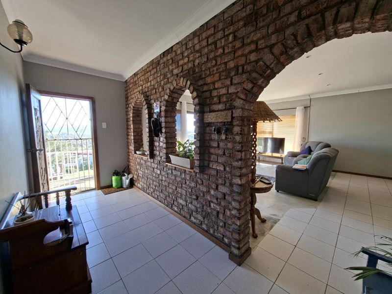 Open plan living area featuring a distinctive exposed brick wall with arched openings, tiled flooring, and direct access to an outdoor balcony.