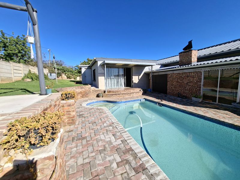Outdoor pool area featuring a swimming pool, brick paving, and a covered patio space adjacent to the main house structure.
