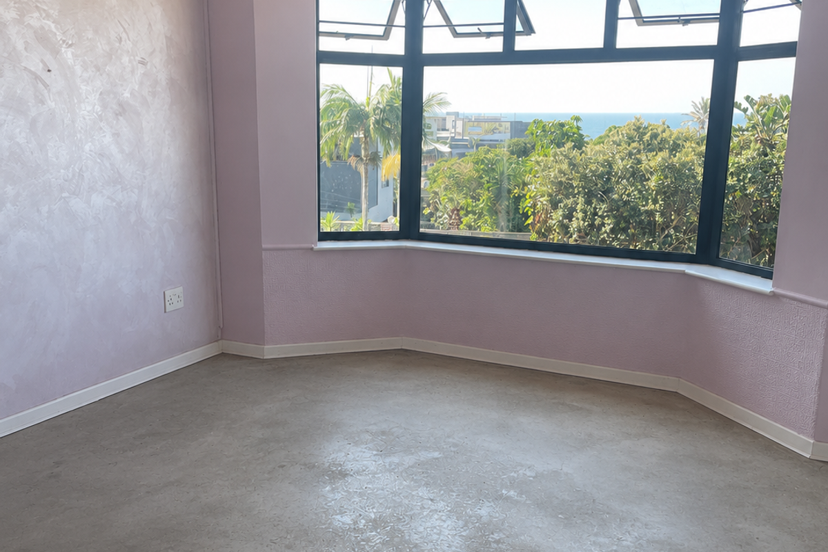 An empty living room featuring a large bay window with coastal views, a split-system air conditioner, and unique textured wall finishes.
