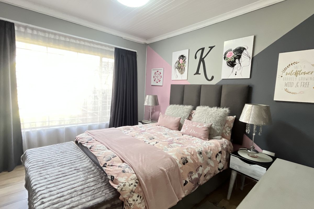 A well-maintained bedroom featuring laminate flooring and a classic timber ceiling, offering a comfortable and inviting living space.
