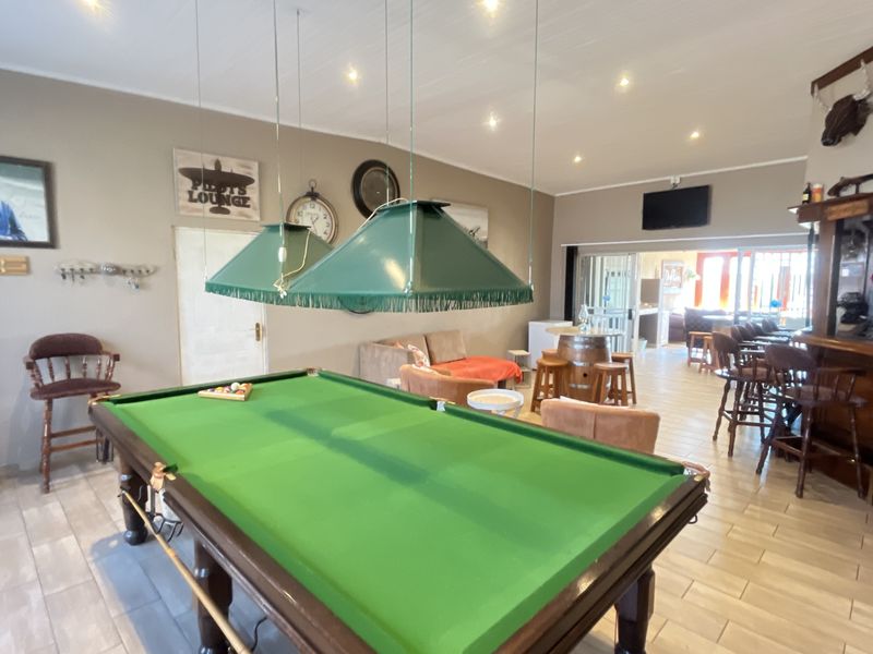 Spacious entertainment area featuring a built-in bar, tiled flooring, recessed lighting, and direct access to the patio through sliding glass doors.