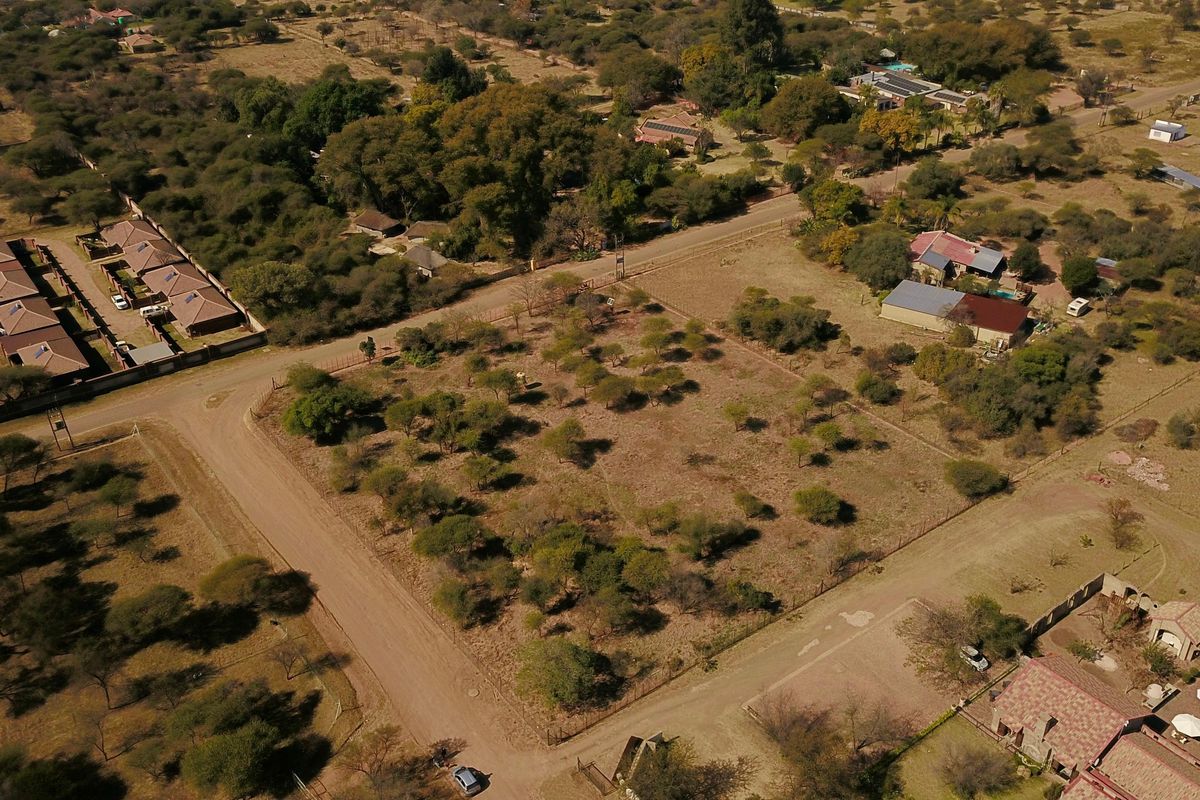 Aerial view of a large, undeveloped plot of land in a rural farm setting, featuring established trees and surrounding residential infrastructure.