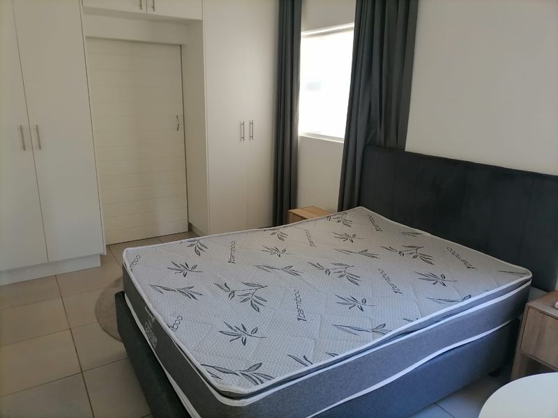A well-maintained bedroom featuring neutral tiled flooring and ample built-in cupboard storage space.