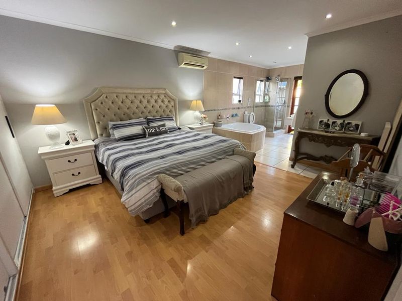 Spacious master bedroom featuring laminate flooring, recessed lighting, air conditioning, and an open-plan en-suite bathroom with a built-in bathtub and glass shower.