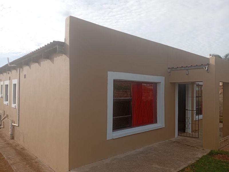 Front exterior view of a single-story house featuring a concrete apron, metal security gate, and metal window frames.