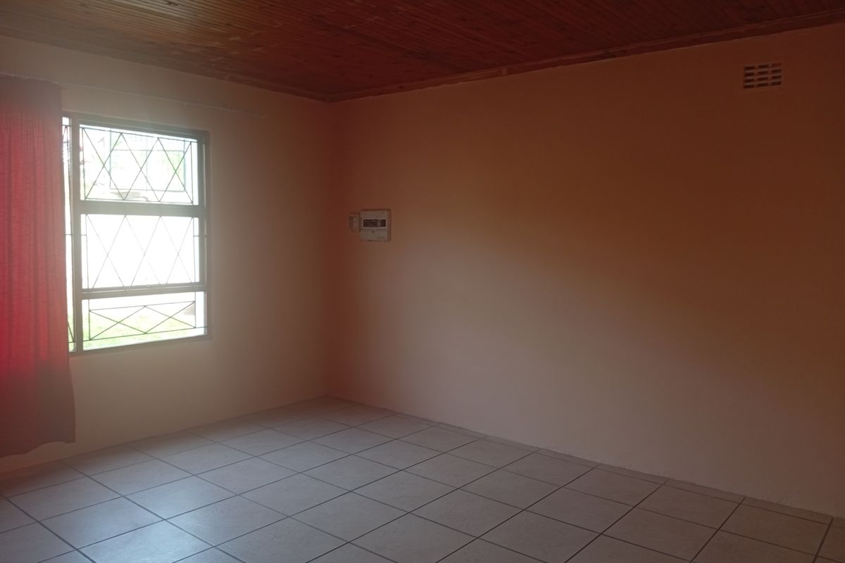 A vacant bedroom featuring tiled flooring, a timber-clad ceiling, and a window fitted with security bars.