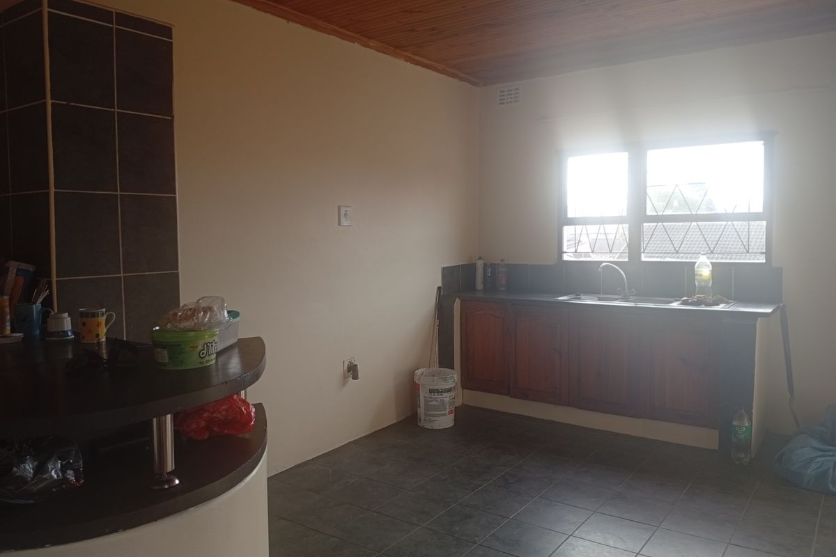 A functional kitchen featuring timber ceilings, tiled flooring, built-in wooden cabinetry, and a breakfast bar, offering a blank canvas for potential updates.