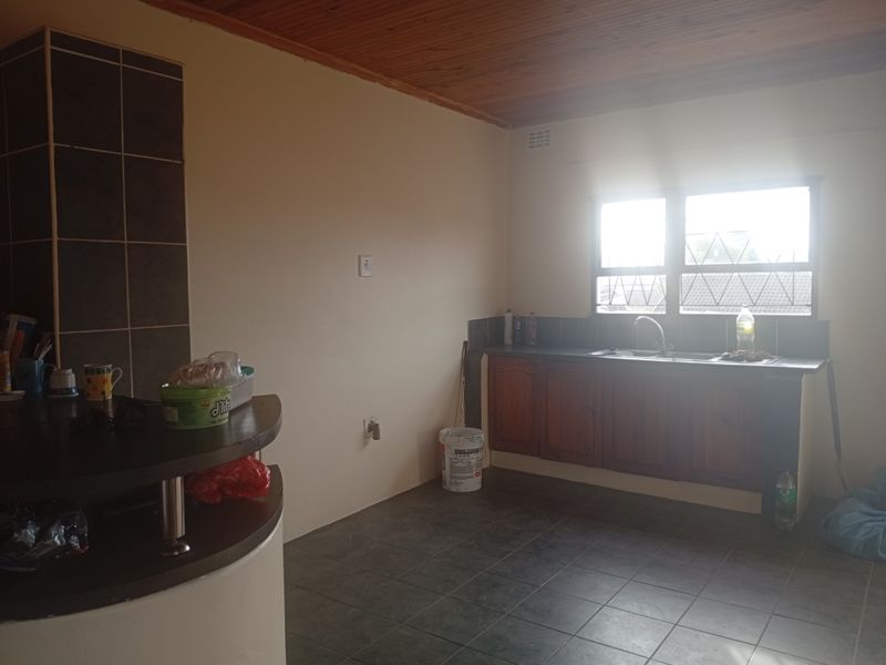 A functional kitchen featuring timber ceilings, tiled flooring, built-in wooden cabinetry, and a breakfast bar, offering a blank canvas for potential updates.