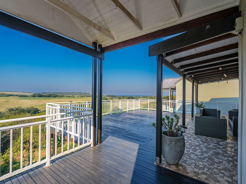 Spacious elevated deck featuring timber flooring, stone tiling, and a covered pergola, offering expansive views of the surrounding landscape.