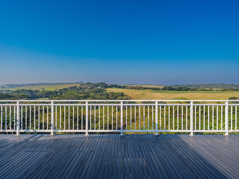 Spacious elevated timber deck featuring a white metal balustrade, offering expansive panoramic views of the surrounding landscape.