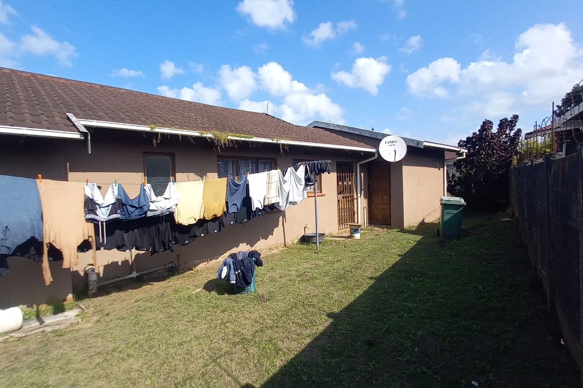 Rear exterior view of the house featuring a lawn area, tiled roof, and satellite dish installation.