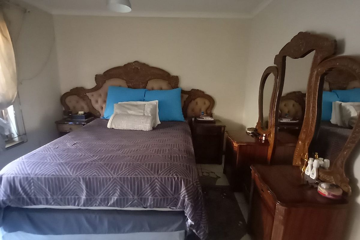 A bedroom featuring tiled flooring and a central pendant light fixture, requiring cosmetic updates to the flooring and general finishes.
