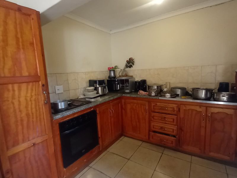A functional kitchen featuring wooden cabinetry, granite countertops, a built-in oven, and tiled flooring, offering a classic layout with potential for modernization.
