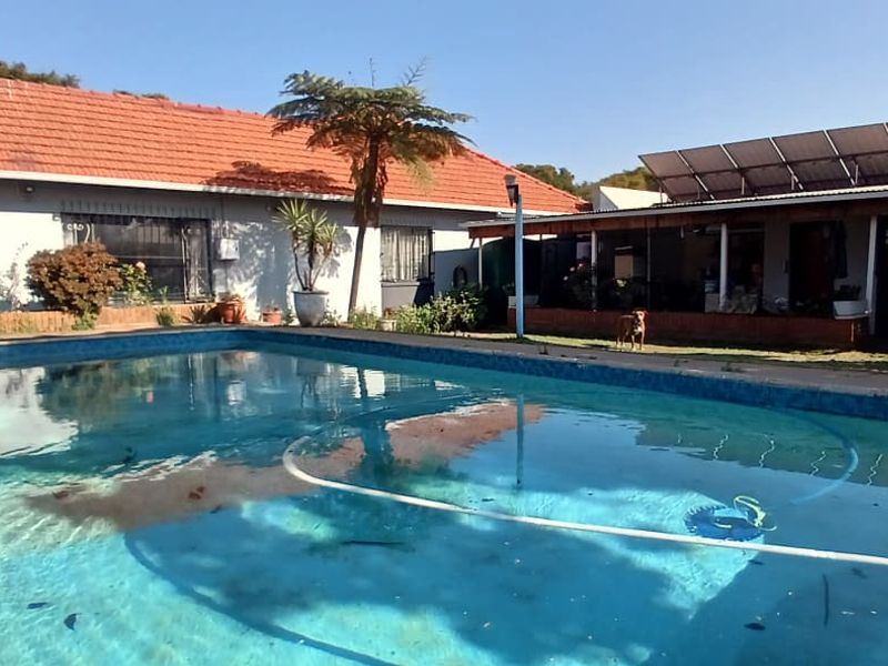 Outdoor pool area featuring a swimming pool, covered patio space, and roof-mounted solar panels on the adjacent structure.