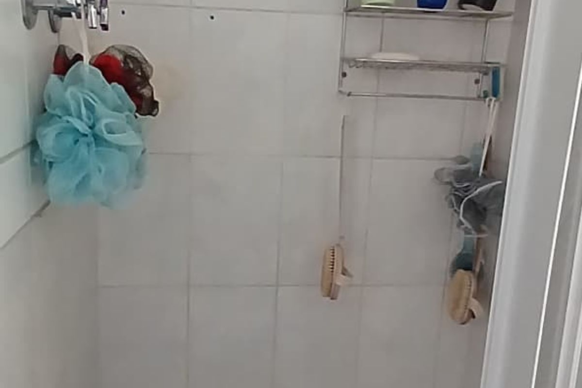 A compact shower enclosure featuring a wall-mounted shower head, tiled walls, and a tiled floor base.