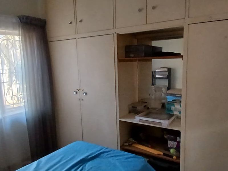 A bedroom featuring extensive built-in cupboards with integrated shelving and security bars on the window.
