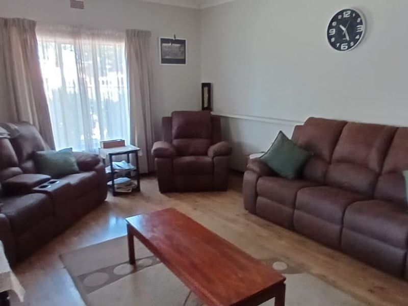 A comfortable living room featuring laminate flooring and a dado rail, providing a functional and neutral space for relaxation.