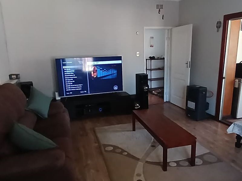 A comfortable living room featuring laminate flooring and a sliding glass door providing access to an adjacent room.