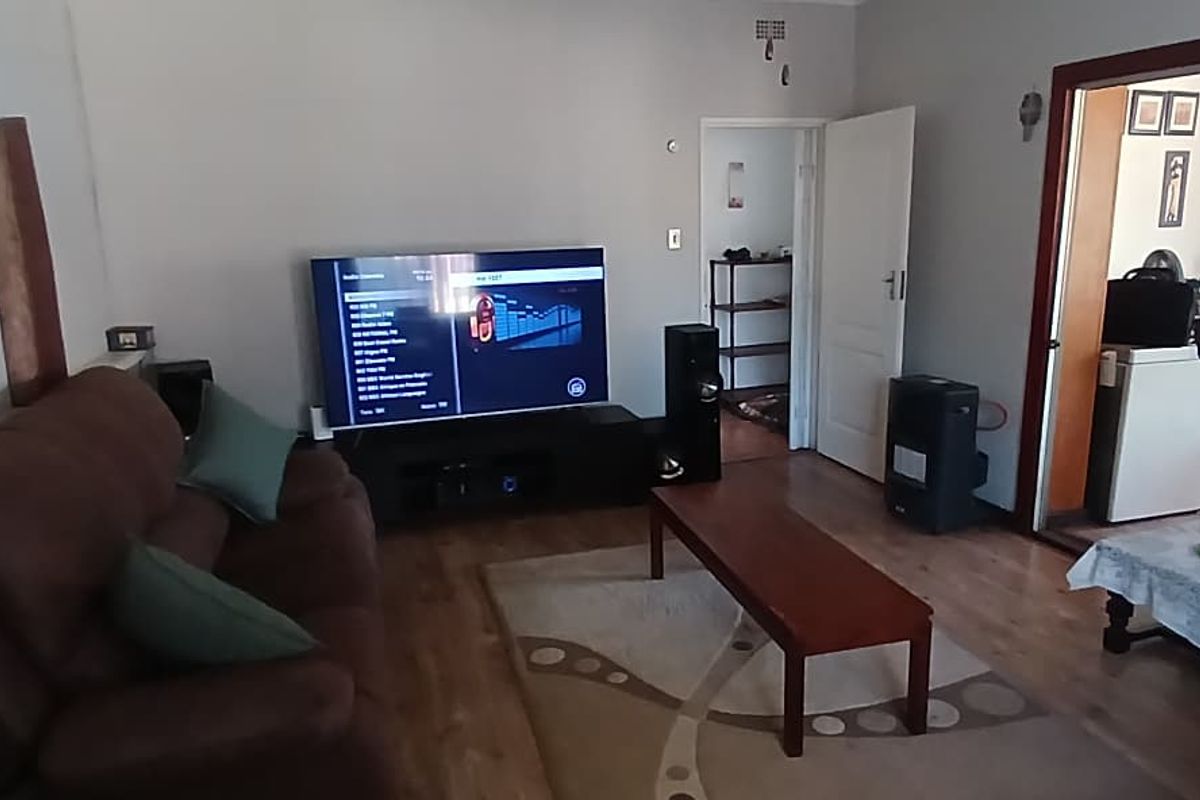 A comfortable living room featuring laminate flooring and a sliding glass door providing access to an adjacent room.