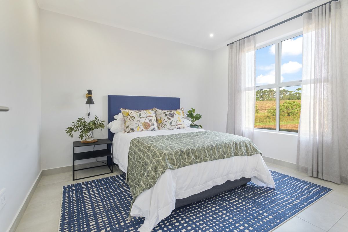 A bright and modern bedroom featuring neutral tiled flooring, recessed lighting, and a large window providing natural light and scenic views.