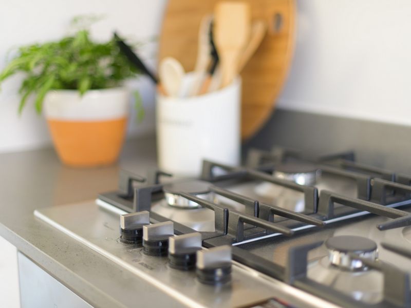 Close-up view of a modern stainless steel gas cooktop integrated into a stone kitchen benchtop.