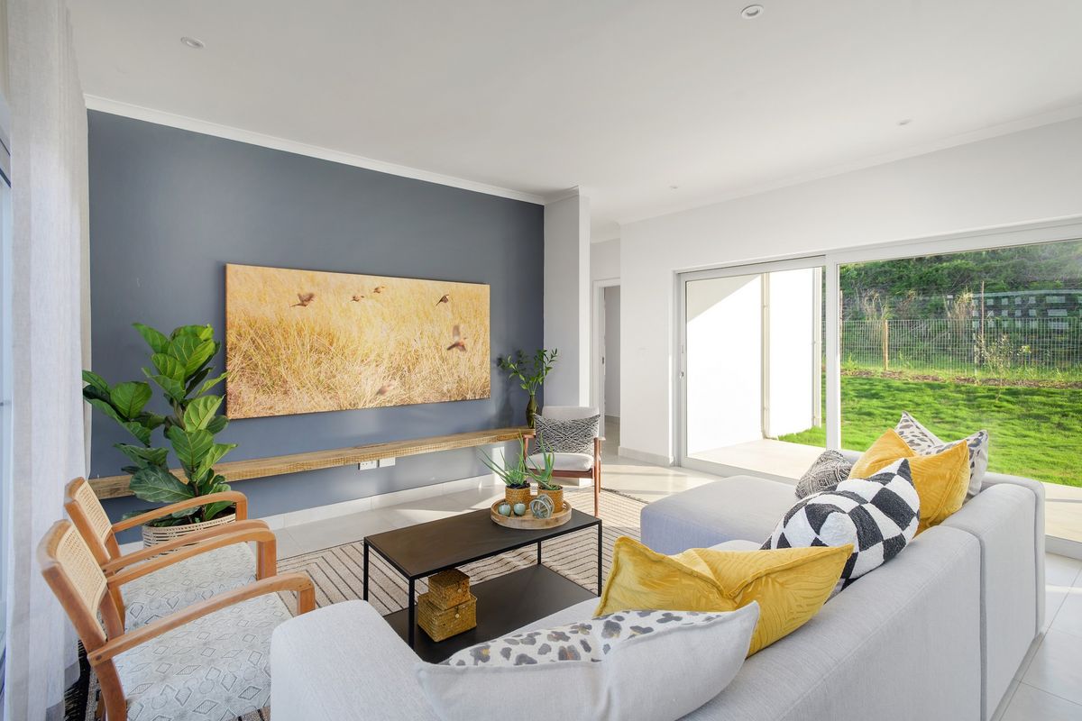 Bright and modern living room featuring a feature wall, floating timber shelf, and large sliding glass doors providing seamless access to the garden.