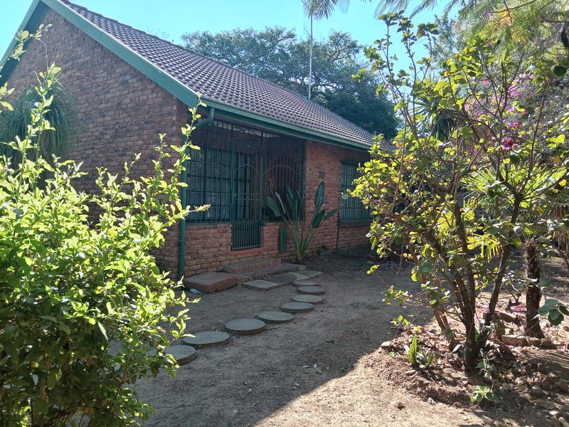 A single-story face brick house featuring a tiled roof, security gates, and a garden path leading to the entrance.