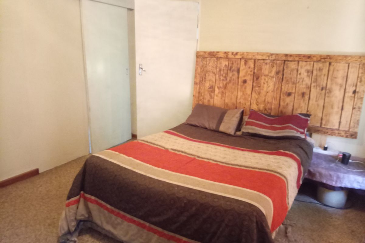 A bedroom featuring a wooden headboard and built-in sliding door cupboards with neutral wall finishes.