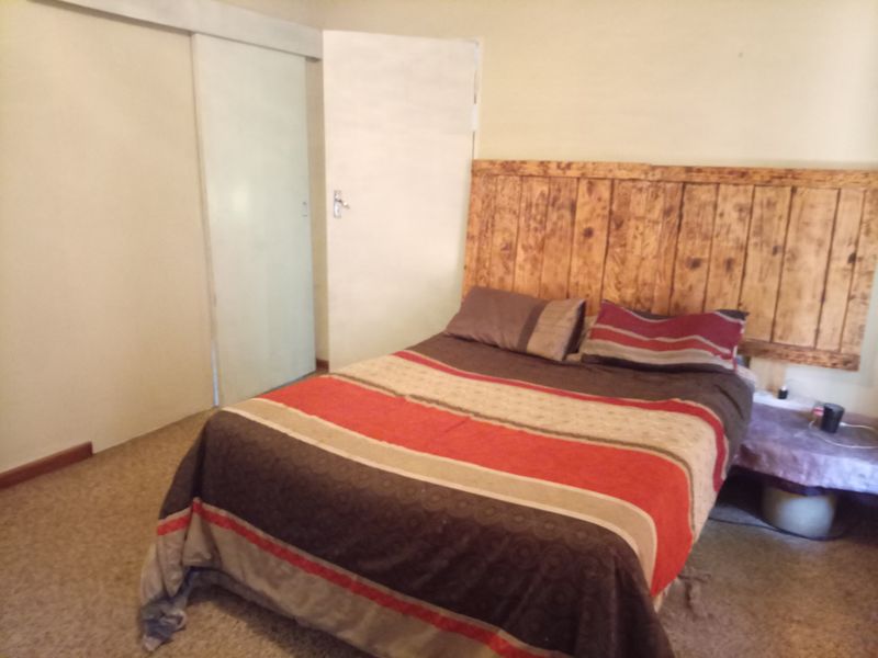 A bedroom featuring a wooden headboard and built-in sliding door cupboards with neutral wall finishes.