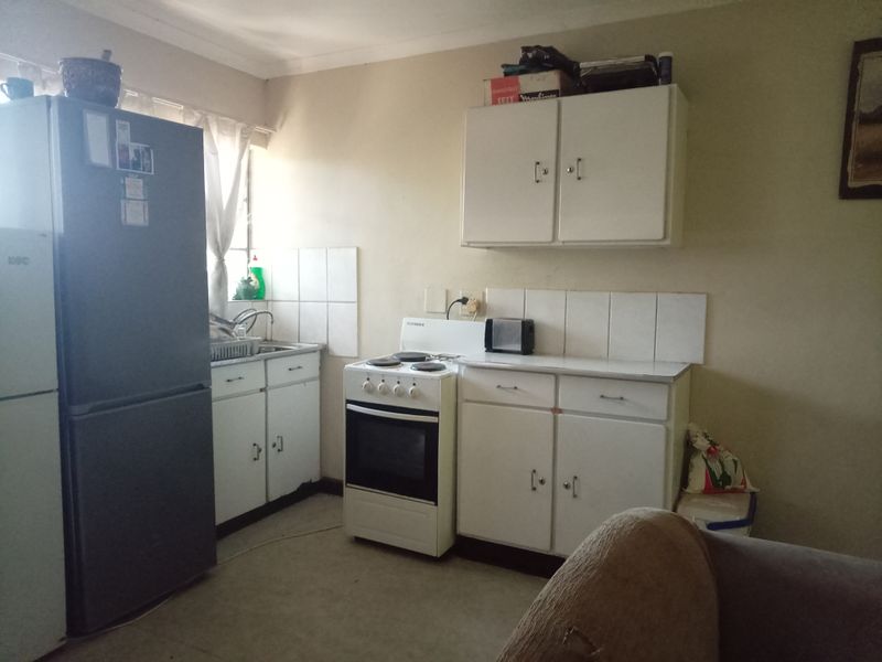 A functional kitchen featuring white cabinetry, a tiled splashback, and a freestanding stove, offering potential for modernization and aesthetic improvement.