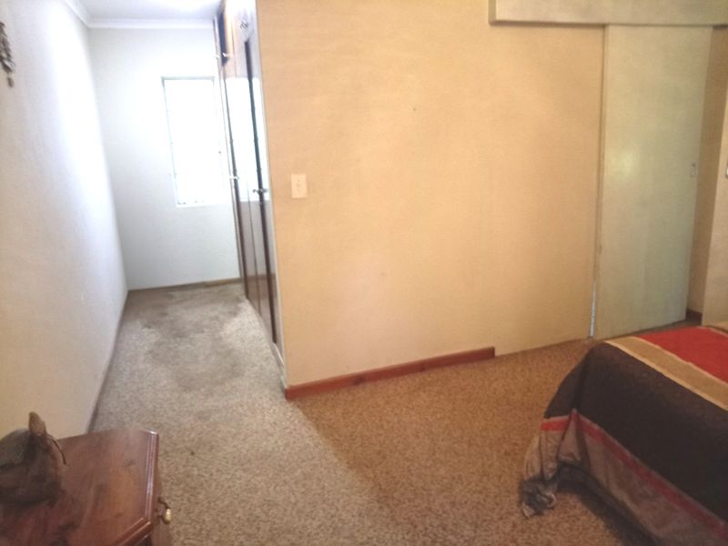 A bedroom featuring built-in cupboards and carpeted flooring, requiring cosmetic updates to improve the overall aesthetic and condition of the space.