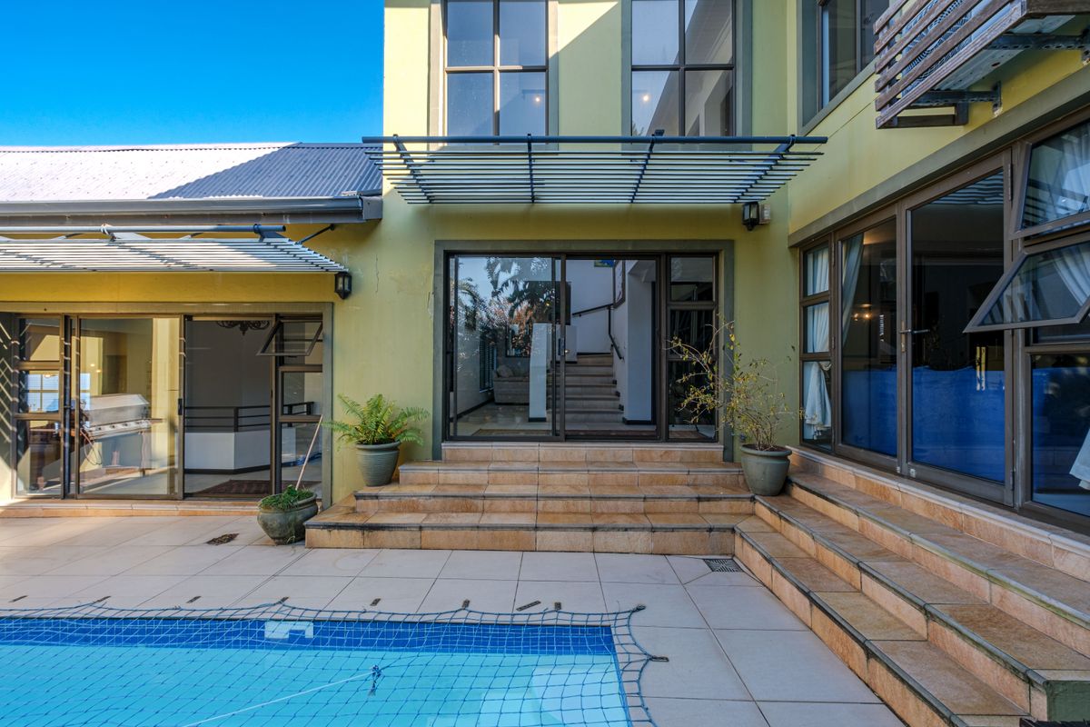 Rear exterior view featuring a tiled patio area, swimming pool, and direct access to the home through large sliding glass doors.