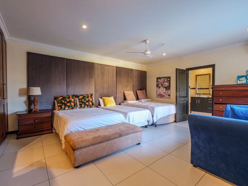 Spacious bedroom featuring built-in cupboards, tiled flooring, ceiling fan, air conditioning, and an adjoining en-suite bathroom.