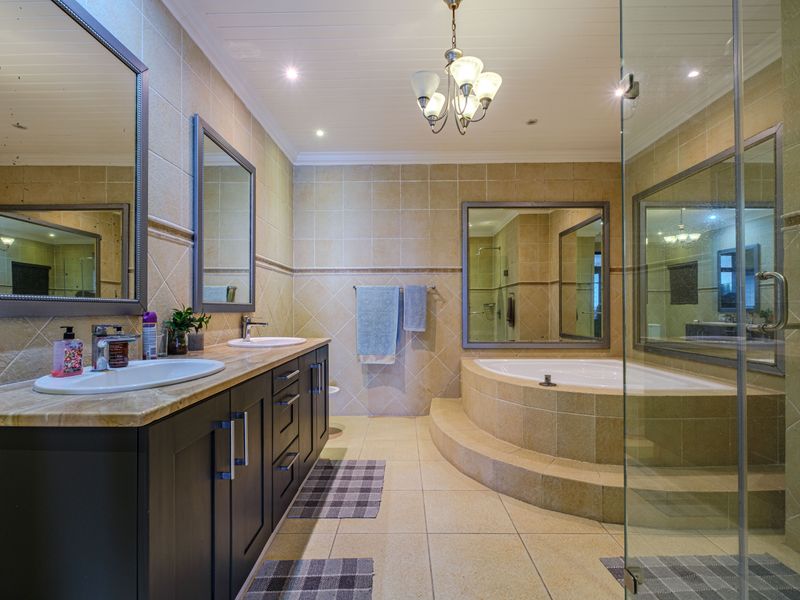 Spacious bathroom featuring a double vanity with stone countertop, a raised built-in bathtub, and a separate glass-enclosed shower with neutral tile finishes.