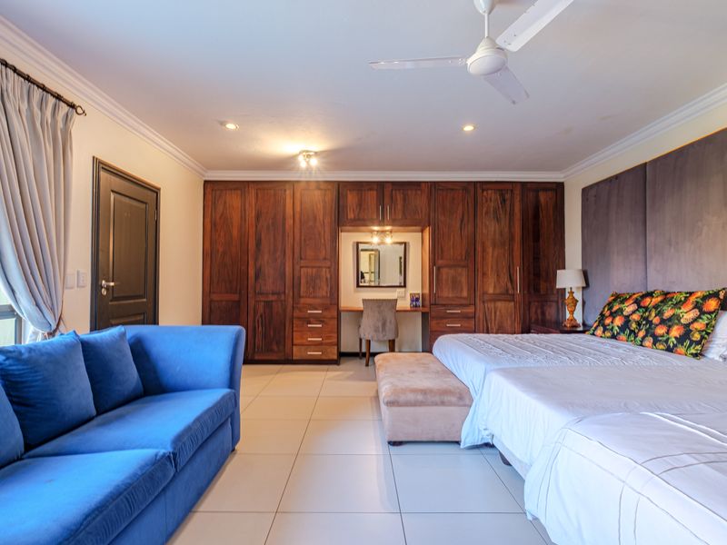 Spacious bedroom featuring extensive built-in wooden cabinetry with an integrated vanity, tiled flooring, and a ceiling fan.