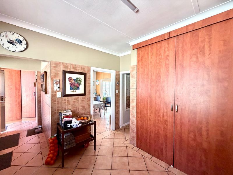A functional hallway featuring tiled flooring, built-in wooden cupboards, and tiled wall accents, providing access to adjacent living spaces.