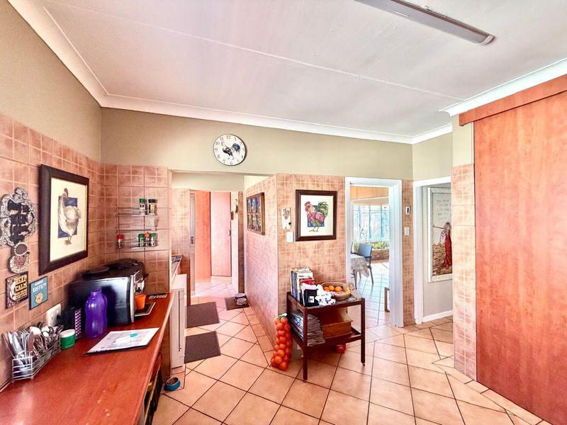 A functional kitchen area featuring tiled flooring and wall splashbacks, with access to adjacent rooms and a sliding door entry.