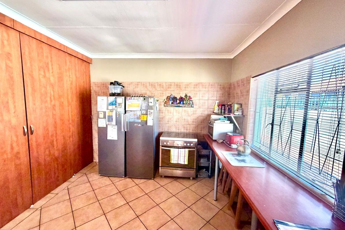 A functional kitchen featuring tiled flooring, a tiled splashback, built-in cabinetry, and a freestanding stove with natural light from the side window.