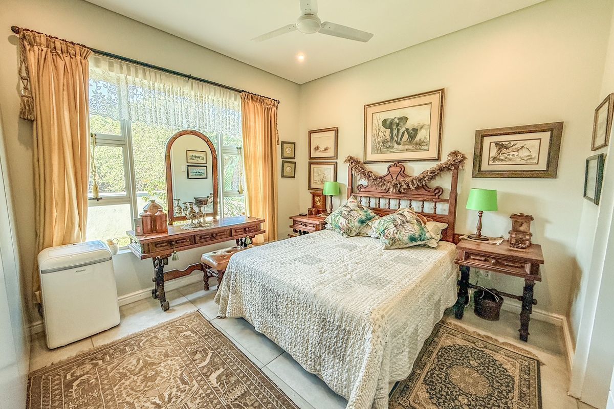 A well-maintained bedroom featuring tiled flooring, a ceiling fan, and a large window providing natural light.