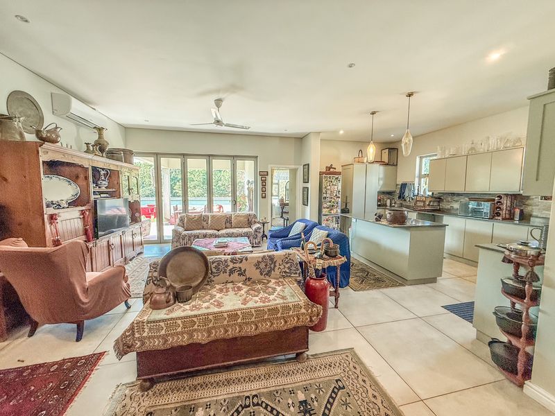 Spacious open-plan living and kitchen area featuring tiled floors, modern cabinetry, a central island, and bi-fold doors leading to an outdoor patio.