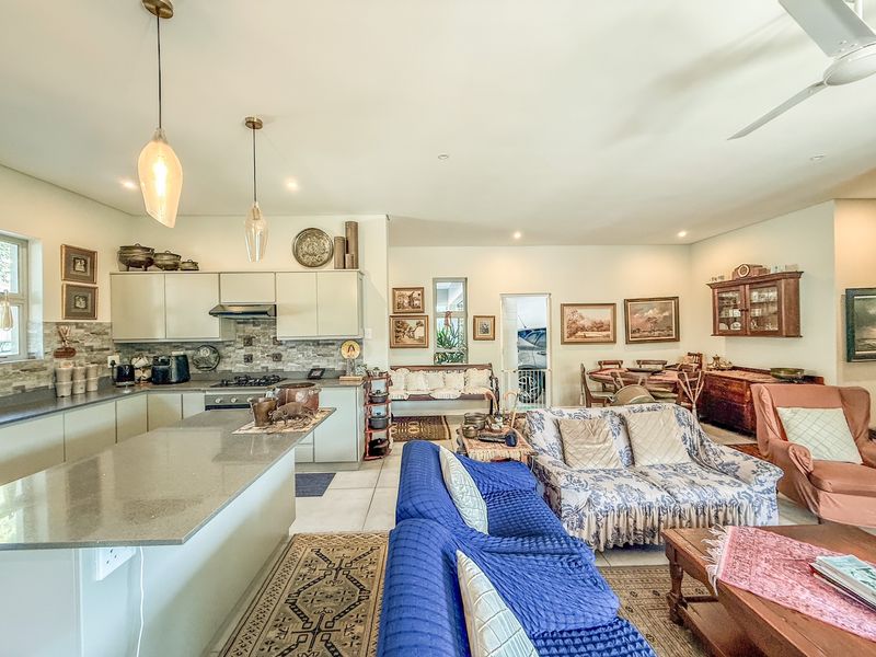 Spacious open-plan living area featuring a modern kitchen with stone countertops, island, and integrated appliances, flowing into a comfortable lounge and dining space.