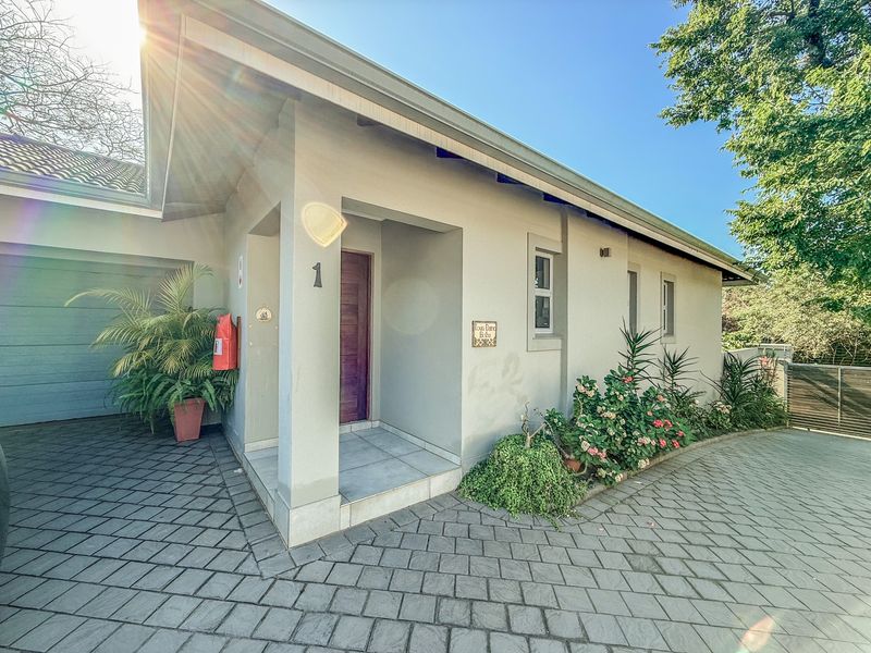 Front elevation of a townhouse featuring a paved driveway, single garage, and a covered entrance with a timber front door.
