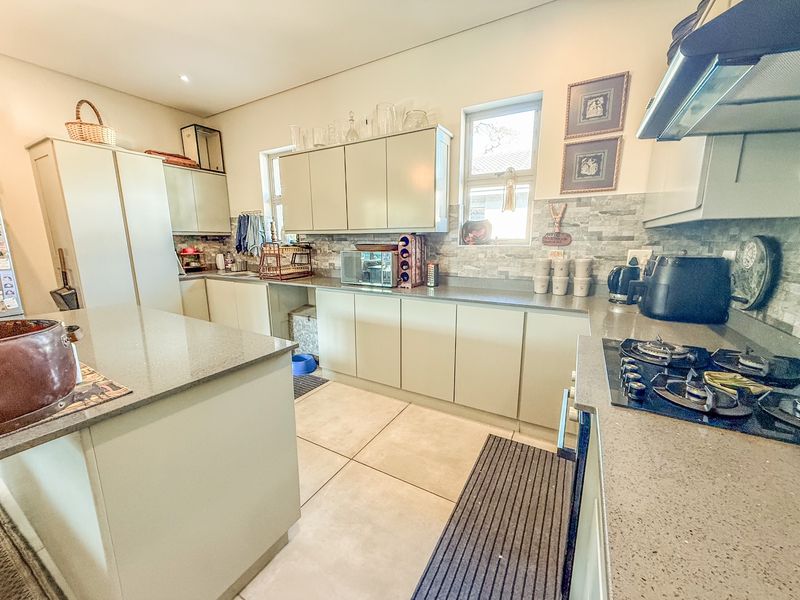 Modern kitchen featuring stone countertops, ample built-in cabinetry, a central island, and a gas hob with an integrated extractor fan.