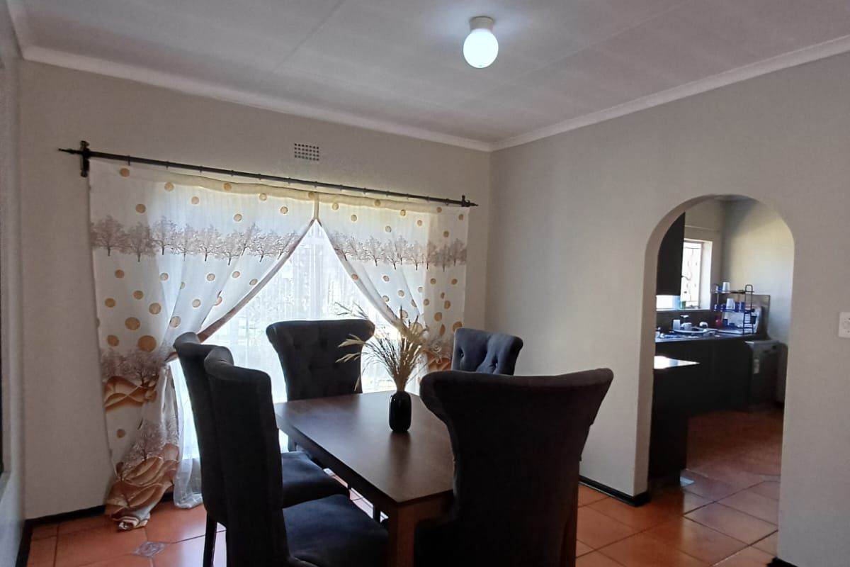 Dining area featuring ceramic tile flooring and an arched entryway leading to the kitchen, providing a functional and connected living space.