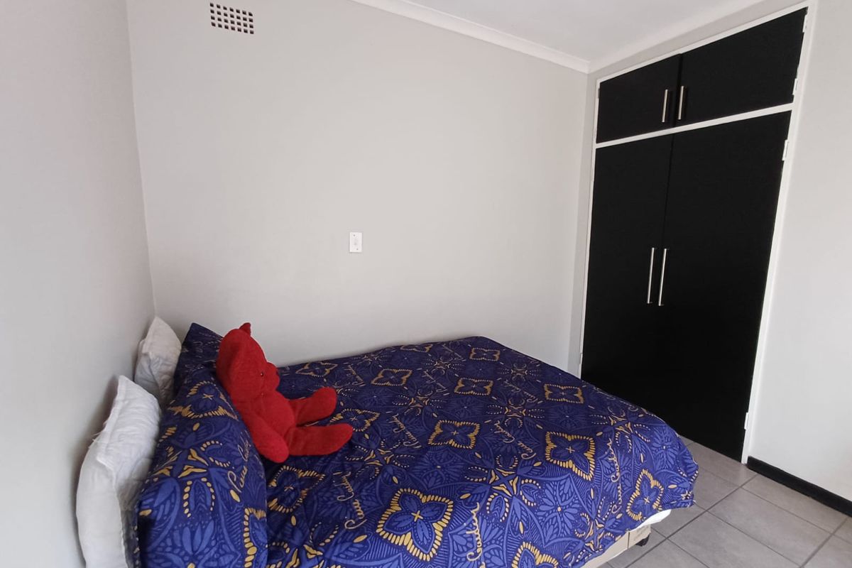 A bedroom featuring tiled flooring and a built-in wardrobe with dark cabinetry.