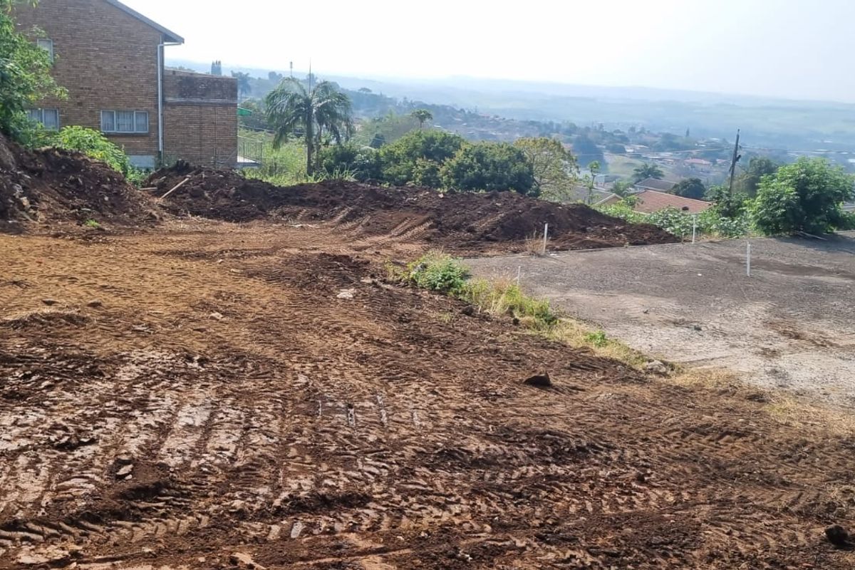 A vacant residential plot featuring excavated earth, a concrete slab foundation, and visible plumbing standpipes, offering potential for new construction.