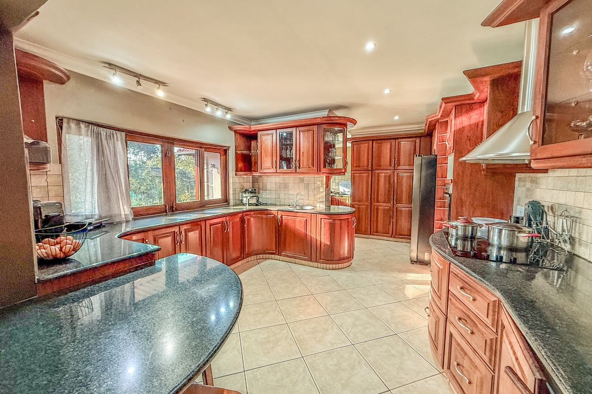 Spacious kitchen featuring extensive wooden cabinetry, granite countertops, a tiled backsplash, and a functional layout with ample storage and workspace.