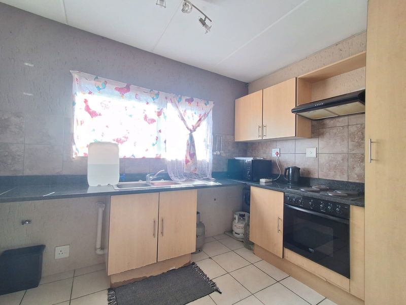 Functional kitchen featuring light wood cabinetry, granite countertops, built-in oven and hob, and tiled splashbacks.